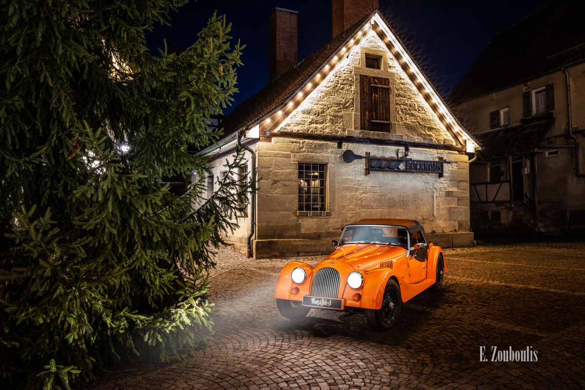 Fotografie eines Morgan 4/4 mit seiner einzigartigen “Morgan Orange” – Farbe vor dem Backhaus am Marktplatz in Gärtringen Fotografie eines Morgan 4/4 mit seiner einzigartigen “Morgan Orange” – Farbe vor dem Backhaus am Marktplatz in Gärtringen
