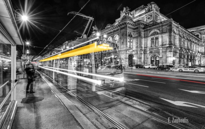 Bild einer Tram vor der Oper in Wien am Opernring. Schwarzweiß mit gelben und roten Light Trails